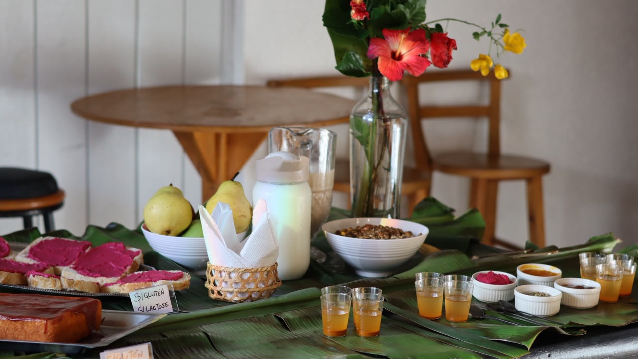 Mesa de café da manhã com pães, frutas e flores